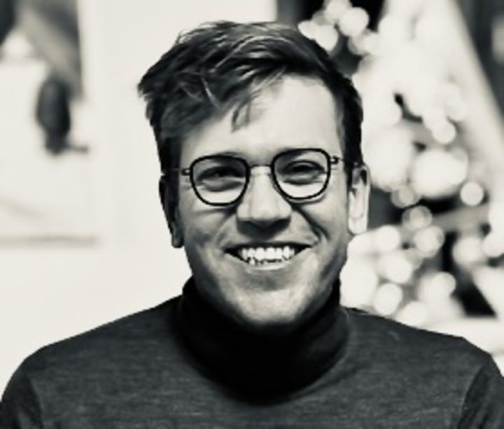 Black-and-white portrait of Jona Engel wearing glasses and a dark turtleneck.
